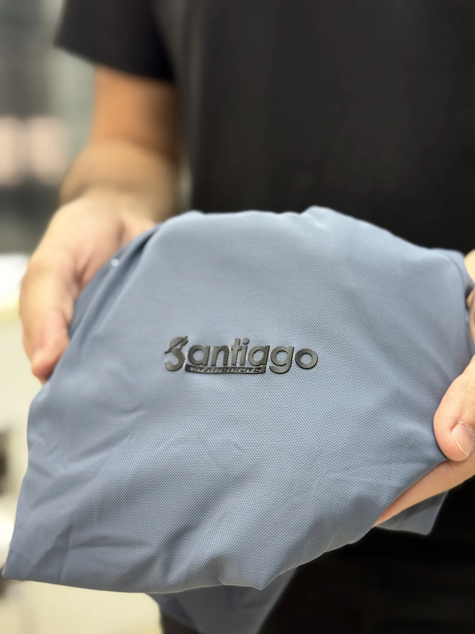Mãos segurando peça dobrada com a marca Santiago aplicada em relevo